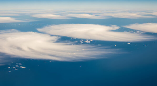 Aerial view of wispy white clouds over deep blue ocean and sky image
