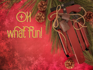 Christmas card Oh What Fun text. Overhead red texture background with holiday wood sled, weathered rustic metal bells and jute twine, long pine branches and needles, and festive pinecones. 
