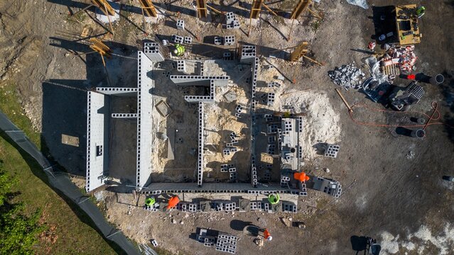 Aerial view of construction site of house foundation with workers building with cinder blocks