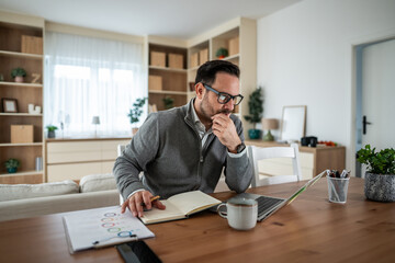 Focused man working remotely from home studying business data