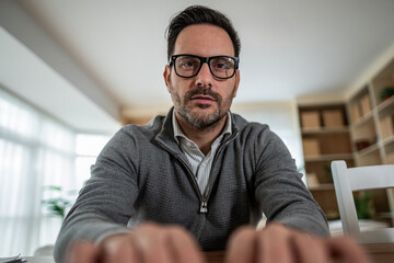 Man in glasses joining an online video call from home