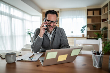 Obraz premium Happy man having phone call working from home office