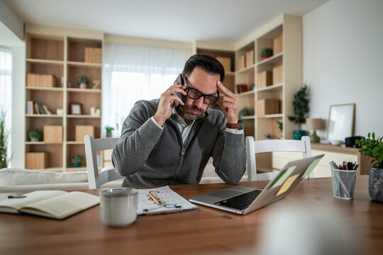 Man working from home experiencing stress during phone call - Powered by Adobe