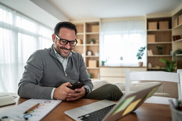 Man smiling using phone working from home office