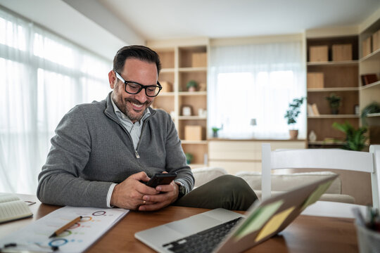 Man smiling using phone working from home office