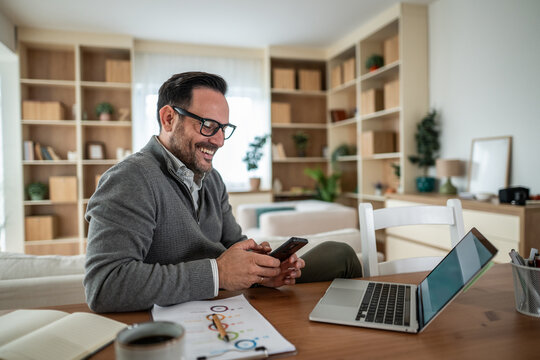 Happy man using smartphone working from home - Powered by Adobe