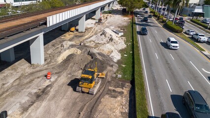 heavy machinery working on road repair next to elevated railway system