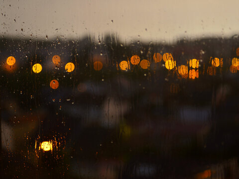 Raindrops on the window in the evening. Bokeh illustration. Wallpaper or background. 