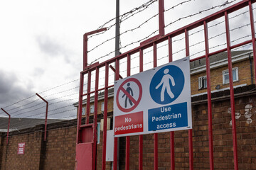 Industrial security gate with barbed wire and no entry safety signs