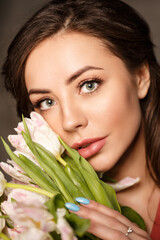 Naklejka premium A beautiful woman with brown hair lovingly holding a vibrant bouquet of pink tulips. This image evokes feelings of warmth, affection, and springtime beauty.