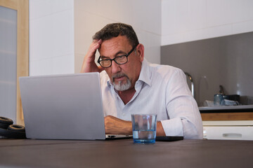 Obraz premium Mature man feeling stress working on laptop at home