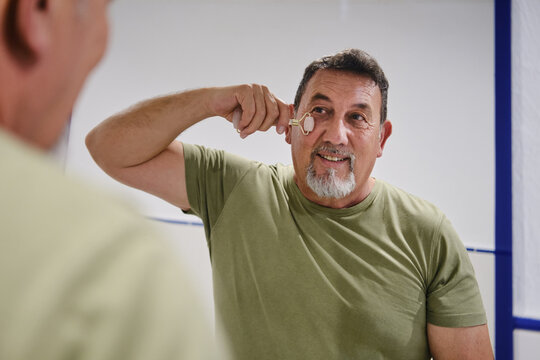 Mature adult man enjoying self-care with natural jade roller