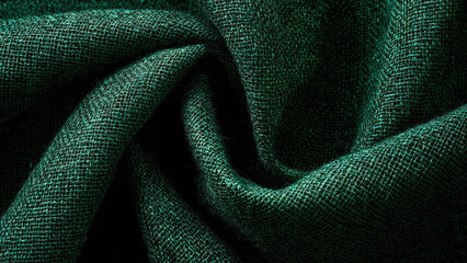 A close-up reveals the rich, dark green texture of a tightly woven fabric, possibly linen or jute, featuring elegant, soft folds and shadows.