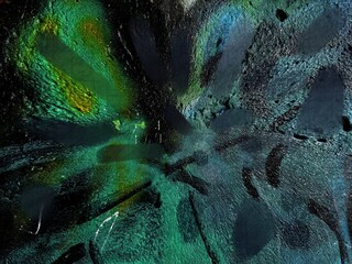 Abstract close-up of a textured surface with vivid green, blue, and yellow tones, featuring layered brush strokes and a dark grunge background for an artistic effect.