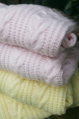 Cozy pastel knitted sweaters stacked neatly for a warm winter look in a cozy environment