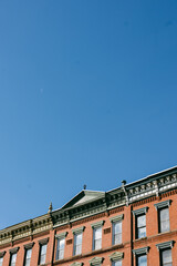 Historic red brick building under clear blue sky with visible moon in the afternoon