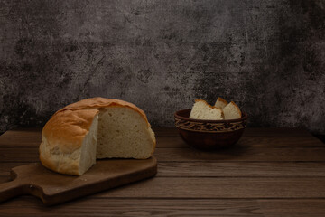 Homemade wheat bread lies on a cutting board on a wooden table. Food.