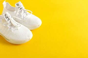 White summer sneakers stand on a yellow background.	