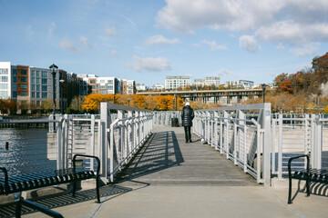 Tranquil walk on a waterfront pier with autumn colors near cityscape in the background