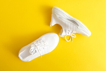 White summer sneakers stand on a yellow background.