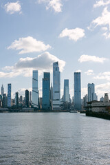 Fototapeta premium Skyline view of modern skyscrapers by the river in a bustling city under a clear blue sky