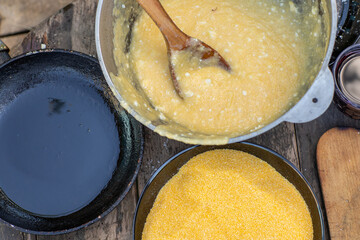 Man Preparing Rustic Polenta with Sheep Cheese on Open Fire. Authentic Countryside Cooking. Rustic Outdoor Meal. Traditional Village Cuisine. Heritage Food Scene