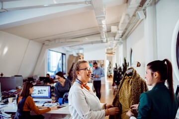 Young adults smiling while designing clothing in fashion studio