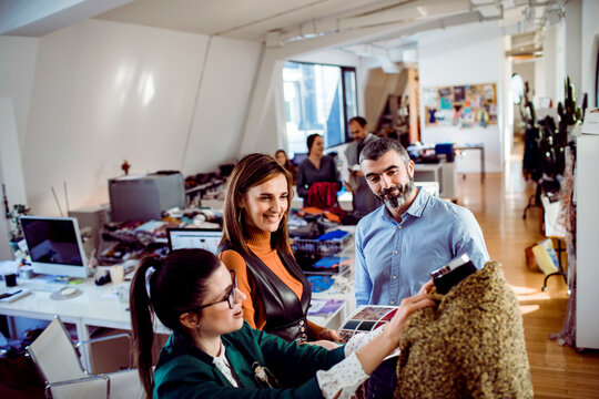 Adult coworkers reviewing fabric samples, smiling in design studio - Powered by Adobe