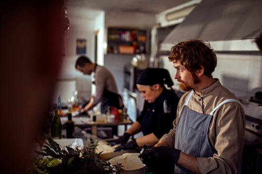 Adult chefs focused while preparing food together in restaurant kitchen