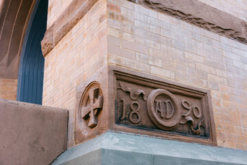 Historic building corner with decorative stonework and year inscription located in a bustling urban setting