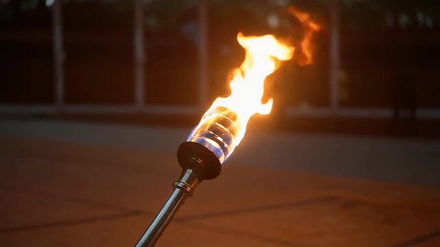 Close-up of a burning tiki torch with bright flame outdoors, creating warmth and dramatic lighting in a dark setting.