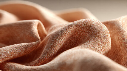 Close-up of soft, light brown woven fabric with delicate folds and intricate texture, emphasizing natural material beauty and earthy tones.