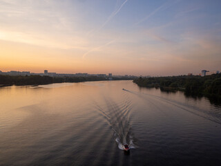 Aerial view of the Moscow River at sunset. A boat is sailing. Kopotnya is on one bank, Brateevo on the other.