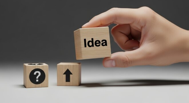 Hand holds a wooden cube with the word Idea above two other cubes marked with a question mark and an upward arrow sign - Powered by Adobe