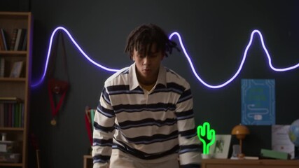Tilt up shot of gen Z male teenager dribbling basketball while having practice in cozy bedroom with neon decor - Powered by Adobe