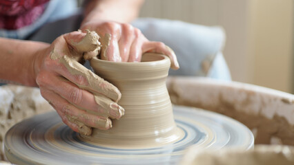 Hands shaping wet clay on a spinning pottery wheel, close-up craft process in a ceramics studio, wheel throwing technique, vessel formation, texture, mindfulness, traditional craftsmanship