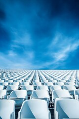 Fototapeta premium Rows of empty white stadium seats under a bright blue sky with clouds
