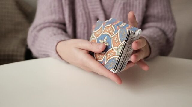 A female astrologer holding and tossing a deck of tarot cards in her hands. 