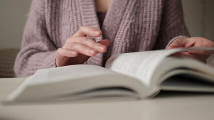 Woman reading an old book. Flipping and old book with stained pages. Flicking through an old textbook closeup, macro shot of paper in university library. Reading and education concept.