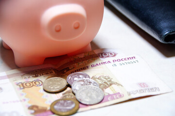 A piggy bank sits on top of a stack of Russian banknotes