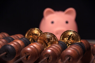 Three golden coins are on a wooden board next to a pink piggy bank