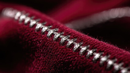 A detailed macro shot showcasing exquisite silver metallic stitching on rich, textured crimson red fabric, emphasizing craftsmanship and luxurious textile detail.