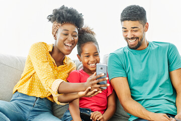 Portrait of mother father and daughter having fun with a smart phone at home, family life, parenting, love and bonding concepts