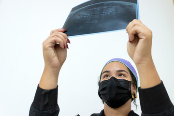 A Colmbian woman dentist is reviewing a patient's X-ray to detect a mouth condition and perform surgery in a hospital office in Neiva, Huila, Colombia. Concept of health and dentistry