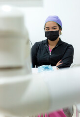 Portrait of a Colombian female dentist sitting in uniform and wearing a mask, looking at the camera inside a dental office in Neiva, Huila, Colombia. Concept of dentistry and copy space