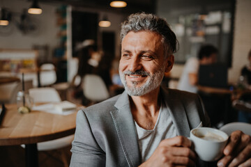 Businessman working remotely from coffee shop, using laptop.