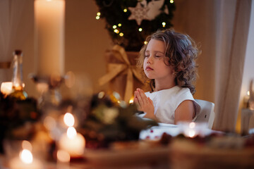 Little girl is praying during Christmas dinner.