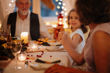Family holding hands in prayer during Christmas dinner.