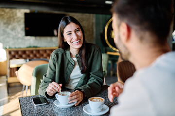 Young couple enjoying conversation and coffee together at an urban cafe table