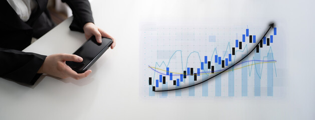 A business professional interacts with a smartphone while financial graphs and charts appear on the desk, symbolizing market growth and strategic insights. Impute